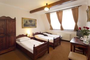 a bedroom with two beds and a desk and a window at Hotel Retman in Toruń