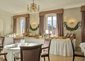 a dining room with tables and chairs and a chandelier at Romantic Hotel Excelsior in Cavalese