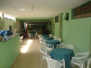 a restaurant with tables and white chairs and blue tables and chairs at Pousada III Poderes in Trindade