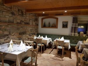 a restaurant with white tables and chairs and a stone wall at Landgasthof Kirchmayer in Farchant