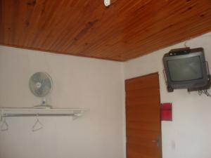 a room with a fan and a tv on the wall at Pousada III Poderes in Trindade