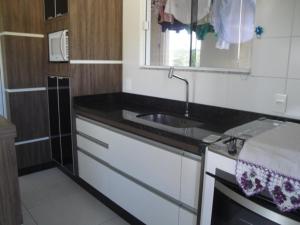 cocina con fregadero y espejo en excelente apto de 3 quartos com suite e vista mar, en Florianópolis