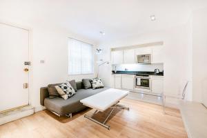ein Wohnzimmer mit einem Sofa und einem Tisch in der Unterkunft Notting Hill Gardens Apartments in London