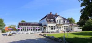 a large white house with purple umbrellas in front of it at Ølsted Kro & Hotel in Ølsted