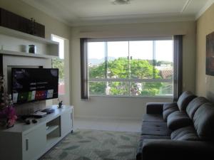 sala de estar con sofá y ventana grande en excelente apto de 3 quartos com suite e vista mar, en Florianópolis