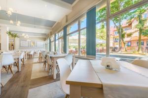 un restaurante con mesas, sillas y ventanas grandes en Delfin, en Krynica Morska