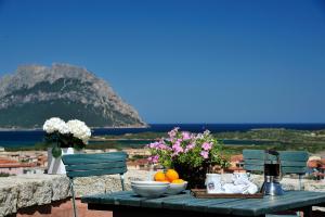 a table with bowls of fruit and flowers on it at Residence L'Ea di Lavru - Appartamenti Mono-Bilo-Trilocali in Porto San Paolo