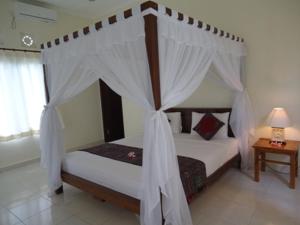 Schlafzimmer mit Himmelbett und weißen Vorhängen in der Unterkunft Bingin Family Bungalow in Uluwatu