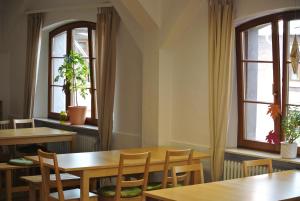 a dining room with tables and chairs and windows at Steffis Hostel Heidelberg in Heidelberg