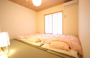 ein großes Bett in einem Zimmer mit Fenster in der Unterkunft 一棟貸切り宿 GuestHouse 嵯峨嵐山 in Kyoto