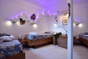ポルト・サン・パーオロにあるResidence L'Ea di Lavru - Appartamenti Mono-Bilo-Trilocaliのベッド2台が備わる客室で、壁に紫色の照明が付いています。