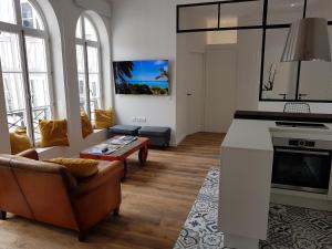a living room with a couch and a table at Nuit Zen Rouen - Centre Historique - Parking - Clim mobile -Balnéo in Rouen