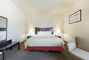 a hotel room with a bed and a couch at Baymont by Wyndham Perryton in Perryton
