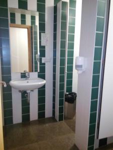 baño con lavabo y azulejos verdes y blancos en Hi Espinho - Pousada de Juventude en Espinho