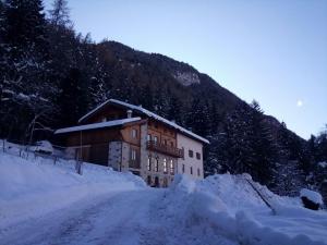 un edificio en la nieve junto a una montaña en Maso Poffer - Cà del Bosco, en Malè