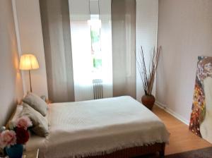 ein Schlafzimmer mit einem Bett und einem Fenster mit Blumen in der Unterkunft LOFTvorSYLT in Friedrichstadt