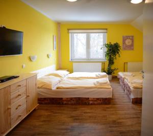 a yellow room with two beds and a window at Penzion Čertovy Kameny in Jeseník