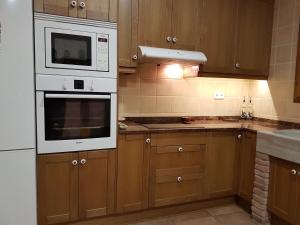 - une cuisine avec des placards en bois et des appareils blancs dans l'établissement Ca la Monica, à Torre de Fontaubella