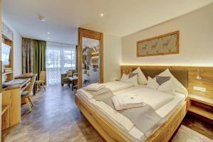 Schlafzimmer mit einem großen weißen Bett und einem Schreibtisch in der Unterkunft Appart-Hotel Wildererstuben in Bodenmais