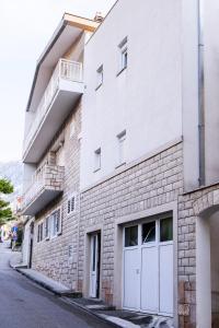 ein weißes Backsteingebäude mit weißen Türen auf einer Straße in der Unterkunft Palloma Studios in Baška Voda