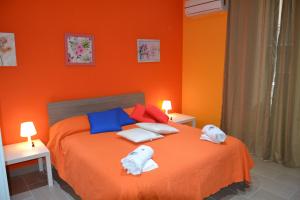 a orange bedroom with a bed with towels on it at Bed Relax Etnaview Self check-in in Zafferana Etnea