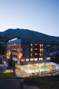 a large building with a swimming pool at night at Hôtel Les Soldanelles in La Toussuire