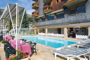 um hotel com uma piscina com mesas e cadeiras em Hôtel Les Soldanelles em La Toussuire