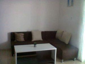 a living room with a brown couch and a white table at Apartmani kod Rade in Pakoštane