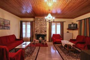 a living room with red furniture and a stone fireplace at Guesthouse Sinoi in Vytina