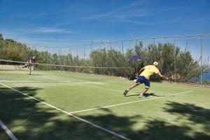 
a man on a court with a tennis racket at Aeolos Beach Resort in Gastouri
