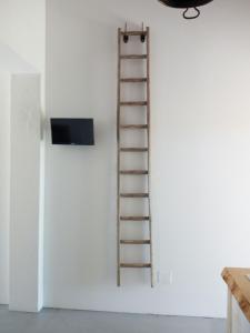 a ladder on a wall next to a tv at Affitto frassanito in Otranto