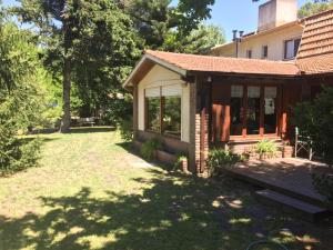 una pequeña casa con un porche en un patio en Alpina Hostería en Villa Gesell