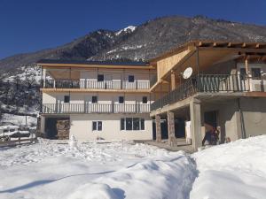 un grand bâtiment dans la neige devant une montagne dans l'établissement Guest House Khergiani, à Mestia