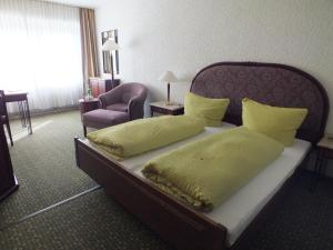 a bed in a hotel room with yellow pillows at Hotel Moselkern in Moselkern