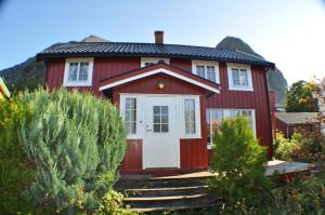 a red house with a white door and some bushes at 5-Bedroom House in Lofoten in Ramberg