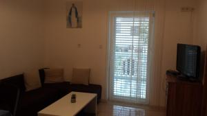 a living room with a couch and a tv and a window at Apartmani kod Rade in Pakoštane