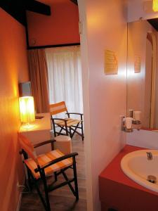 uma casa de banho com 2 cadeiras, uma mesa e um lavatório. em L'Auberge des Collines em Granges-Les-Beaumont