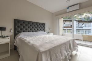 Un dormitorio blanco con una cama grande y una ventana en Boreas Carilo en Cariló