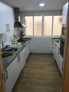 a large kitchen with white cabinets and a sink at Infantes 8-4-30 in Sanlúcar de Barrameda