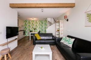 a living room with a black leather couch and a table at Hofwestdijk in Vrouwenpolder