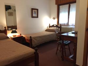 a hotel room with two beds and a desk and a window at Alpina Hostería in Villa Gesell