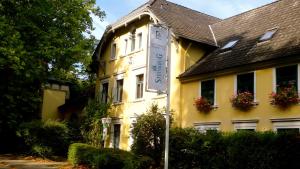 un bâtiment jaune avec un panneau devant lui dans l'établissement Hotel Restaurant Steinkrug, à Wennigsen