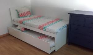 a small white bedroom with a bed and a dresser at Apartamento Paola. Prepirineo. Senderismo, relax... in La Puebla de Castro