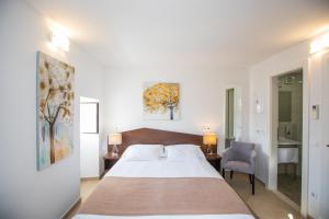 a white bedroom with a bed and a chair at Villa Four Winds in Dubrovnik