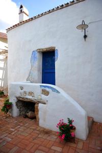 biały budynek z niebieskimi drzwiami i schodami w obiekcie B&B Corte San Lussorio w mieście Oliena