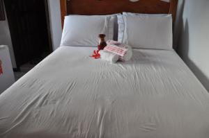 uma cama branca com uma garrafa e toalhas em Amendoeira Hotel da Vila em Morro de São Paulo