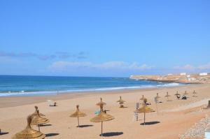 a group of umbrellas on a beach with the ocean at Taddart Aglou in Aglou