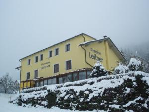 ein großes gelbes Gebäude mit Schnee drauf in der Unterkunft Pension Leitner in Hermagor