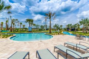 una piscina en el complejo con bancos y palmeras en Romeo Circle #239854 Townhouse, en Kissimmee