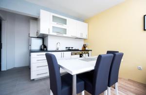 cocina con mesa blanca y sillas azules en Sunrise Inn Sarajevo, en Sarajevo 16 fotos más